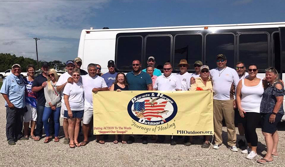 group with Patriots & Heroes banner outside of a coach