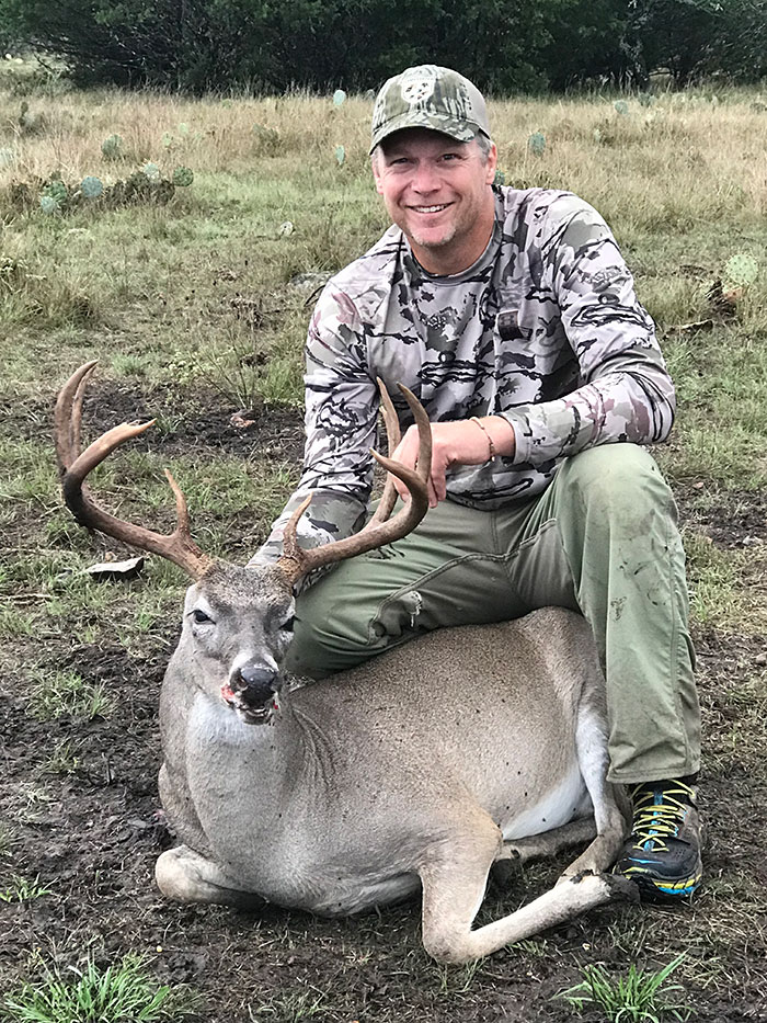 Smiling veteran hunter sitting on buck