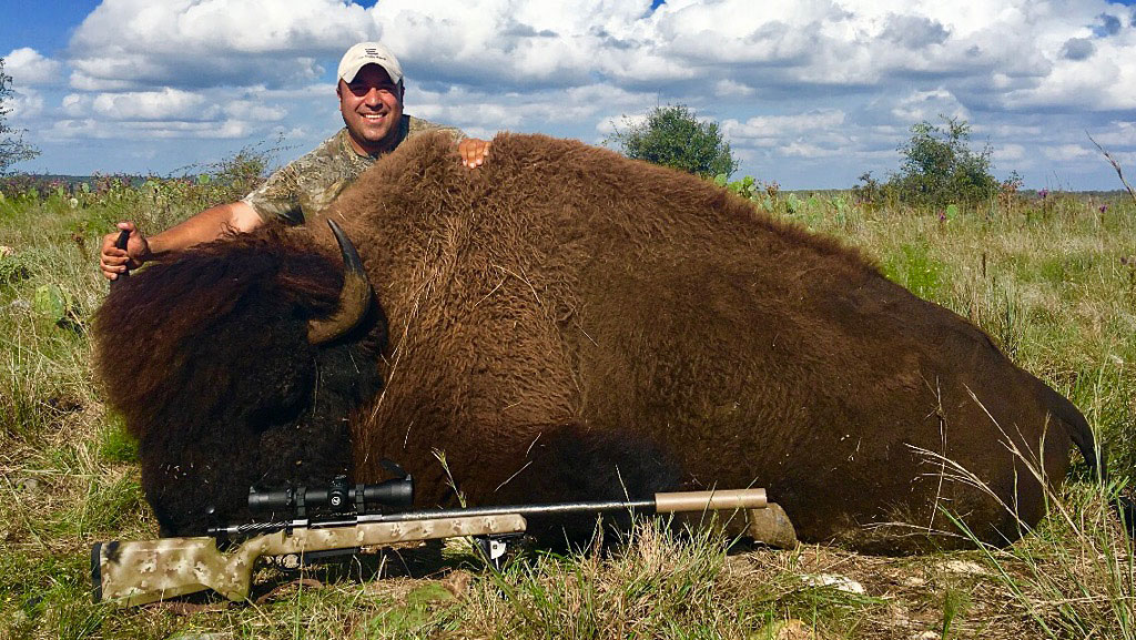 happy man outdoors with huge buffalo he hunted