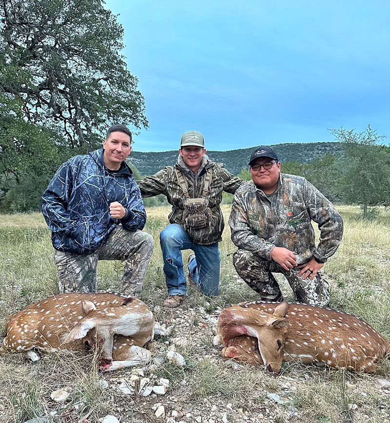 three smiling new friends with two deer hunt in the outdoors